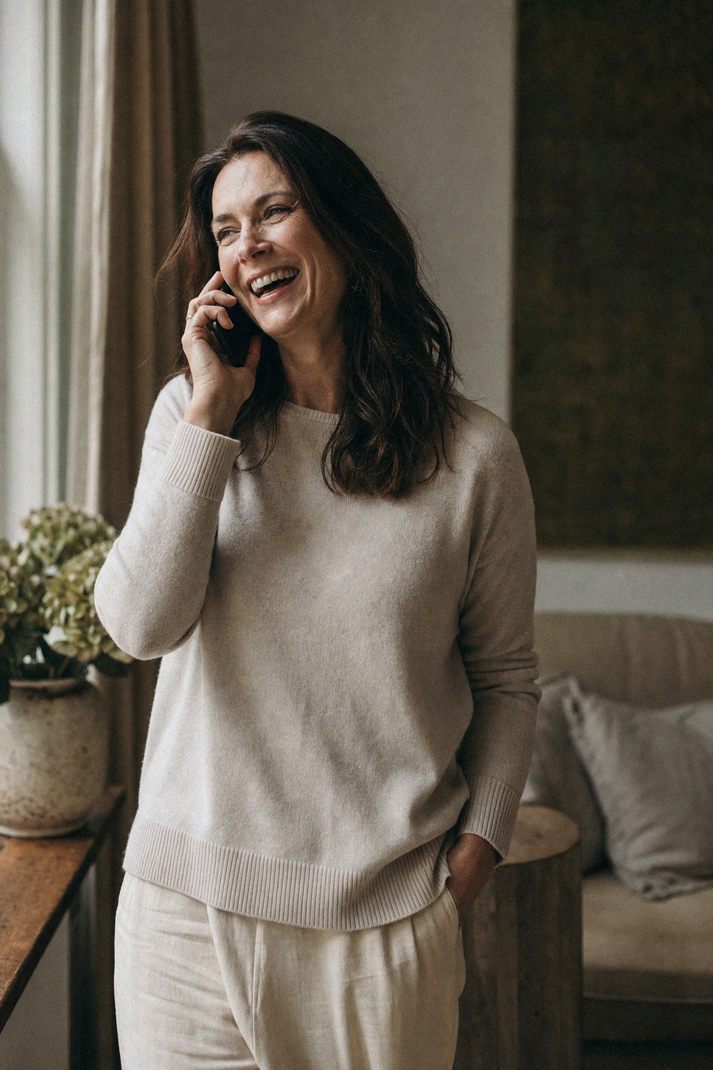 Woman laughing during a phone call at home